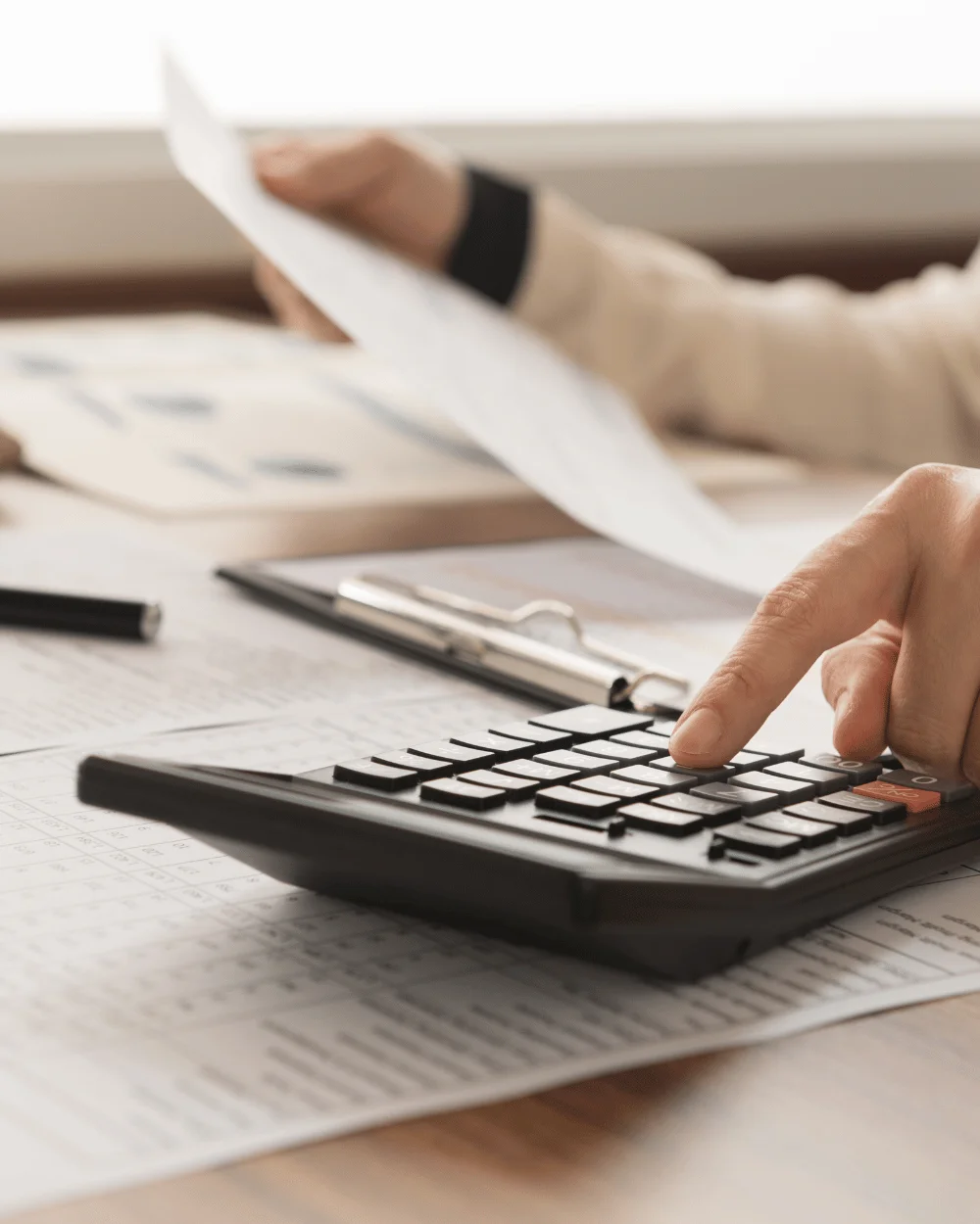 Singapore SME business owner reviewing accounts and spreadsheets with calculator