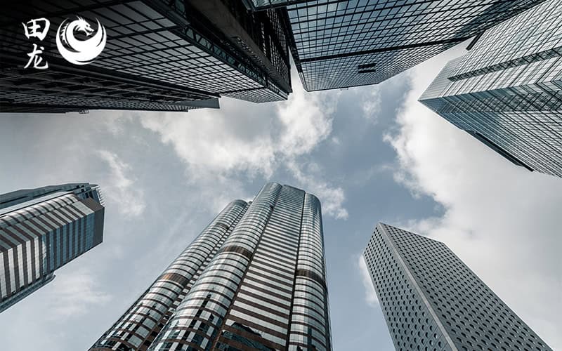 Low-angle view of modern skyscrapers against a cloudy blue sky.