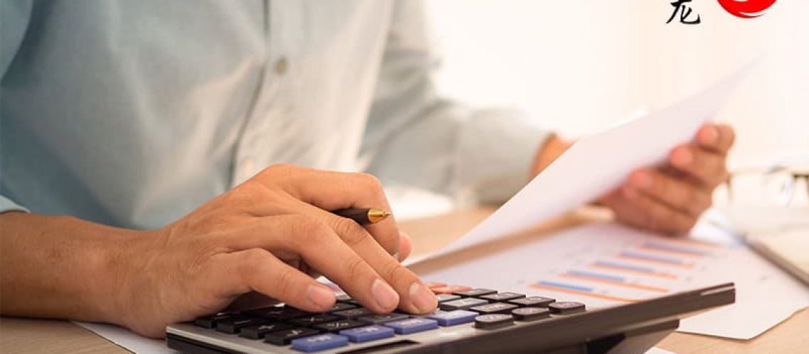 Accountant using a calculator and reviewing financial documents