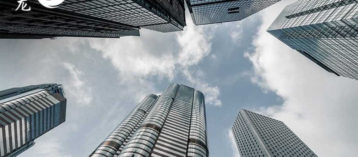 Low-angle view of modern skyscrapers against a cloudy blue sky.